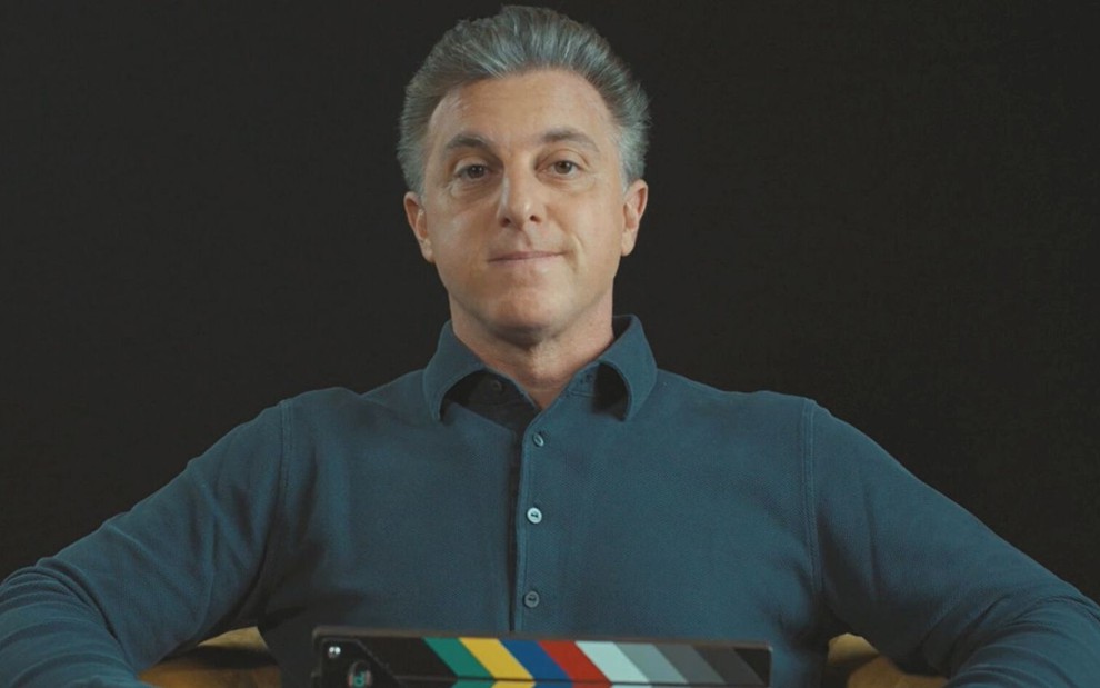 Luciano Huck usa camisa enquanto dá entrevista em um cenário com fundo escuro