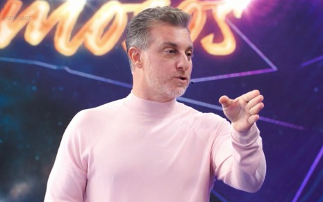 Luciano Huck com uma camisa rosa no palco do Domingão