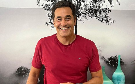 O ator e apresentador Luciano Szafir no cenário do seu programa Casa Szafir; ele está olhando para a câmera e sorrindo em frente a um cenário