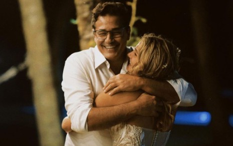 Luciano Szafir de camisa branca, sorridente, abraçando Sasha, de vestido de noiva