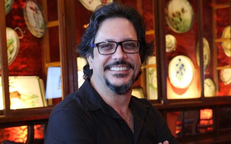 Lucio Mauro Filho sorri e usa óculos em foto de divulgação