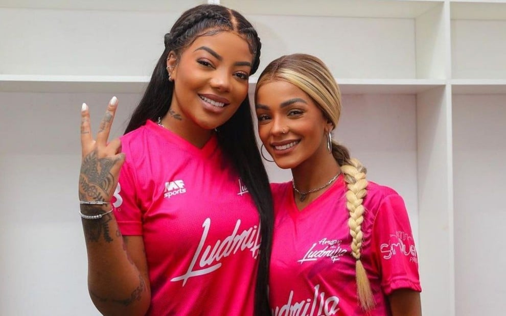 Ludmilla e Bruna Gonçalves em foto publicada no Instagram; as duas estão em um vestiário, abraçadas, sorrindo e vestem o mesmo uniforme de futebol rosa estampado com o nome 'Ludmilla'