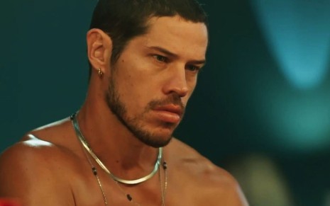 Em cena de Vai na Fé, José Loreto está sem camisa, olhando para alguém triste