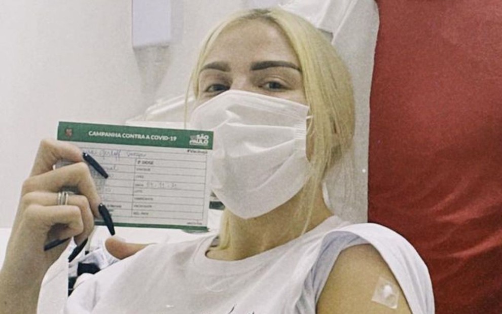 Luísa Sonza de máscara e com o cartão de vacinação da prefeitura de São Paulo após tomar vacina