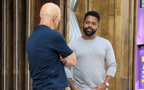 De costas na imagem, Hélio (Luiz Guilherme) conversa com Bernardo (Fábio Ventura) na novela