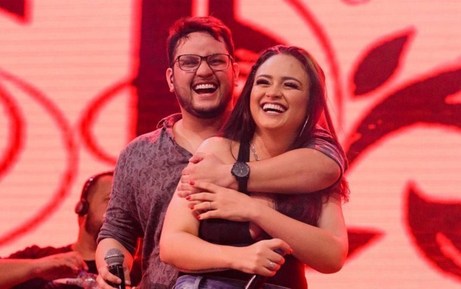 Cantor Maurílio abraça cantora Luiza, enquanto os dois seguram microfones