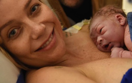 Deitada em uma cama de hospital, Luiza Possi está com o bebê Matteo apoiado no peito