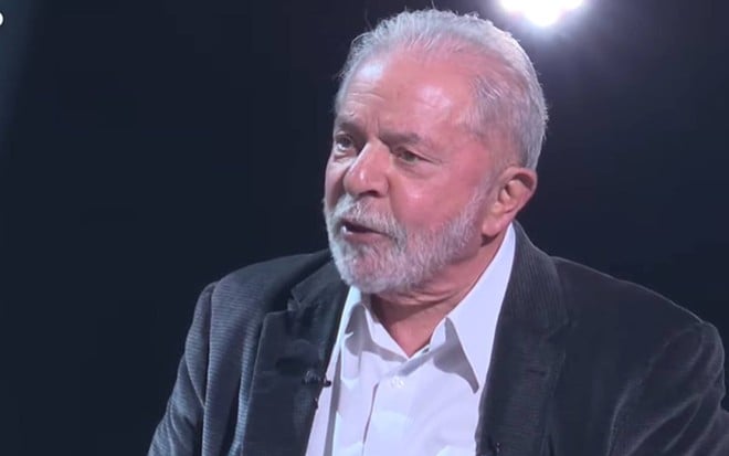 Lula veste camiseta branca, terno preto e olha para o lado