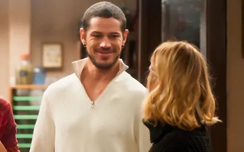 Em cena de Vai na Fé, José Loreto usa camisa branca e está sorrindo para Carolina Dieckmann, que está de costas