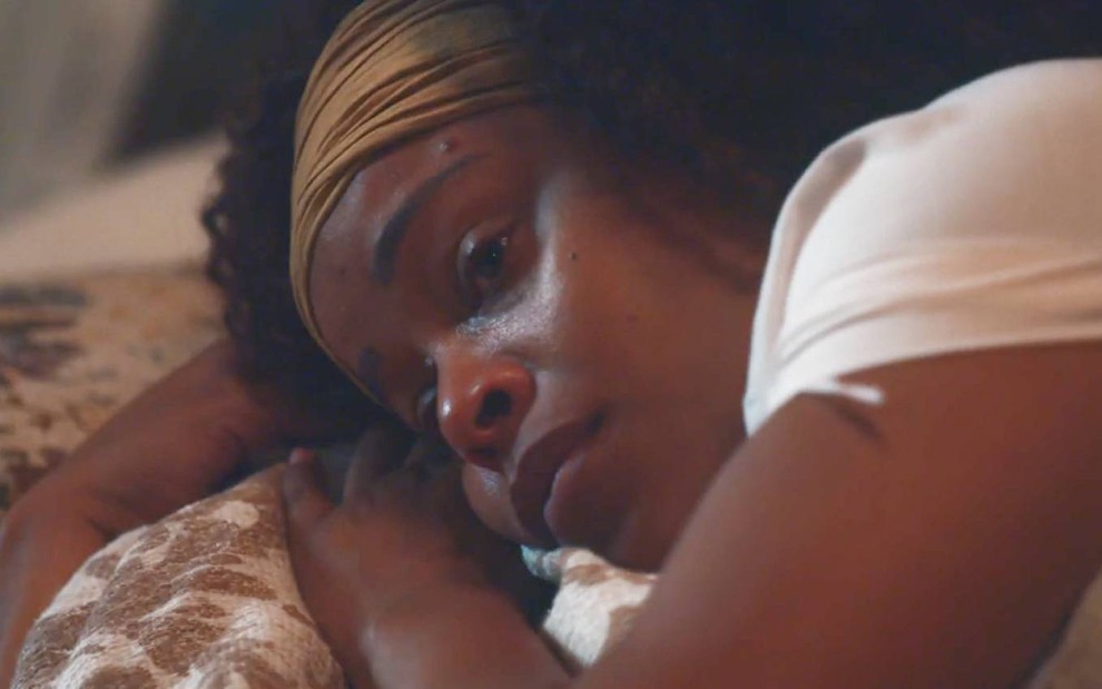 A atriz Roberta Rodrigues deitada em uma cama com expressão triste em cena de Nos Tempos do Imperador