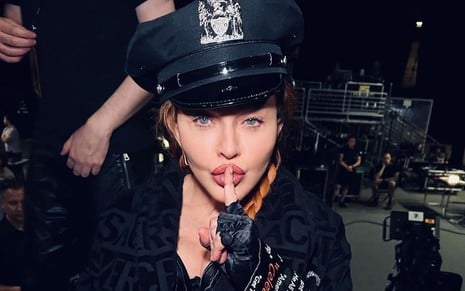 Vestida com um quepe policial, Madonna coloca o dedo na boca como se pedisse silêncio