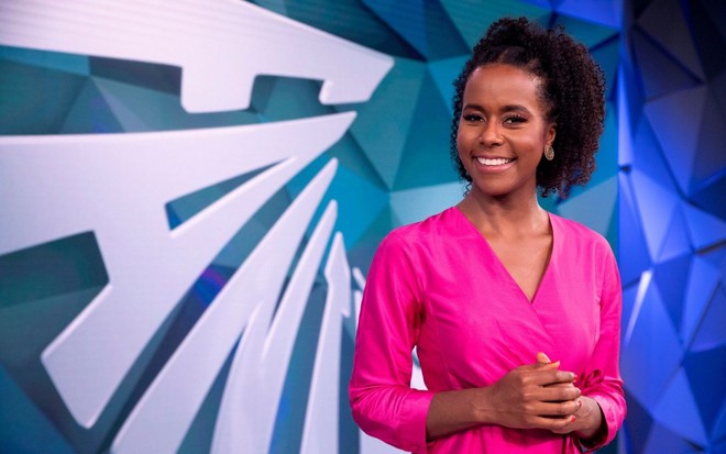 Cenário do Fantástico com Maria Júlia Coutinho à frente, de vestido rosa.