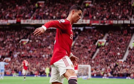 Jogador Cristiano Ronaldo, do Manchester United, vestindo uniforme vermelho e branco, correndo com a bola