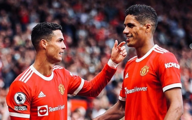 Raphael Varane e Cristiano Ronaldo com a camisa do Manchester United em um jogo de Champions e comemorando um gol