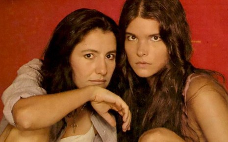 As atrizes Cassia Kis e Cristiana Oliveira posam para foto como Maria e Juma em frente a fundo vermelho, na época de Pantanal (1990)