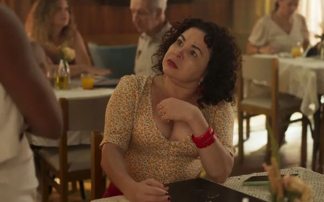 A atriz Suzy Lopes como Cira em Mar do Sertão; ela está sentada, olhando para o lado com cara de surpresa enquanto leva a mão em direção ao peito