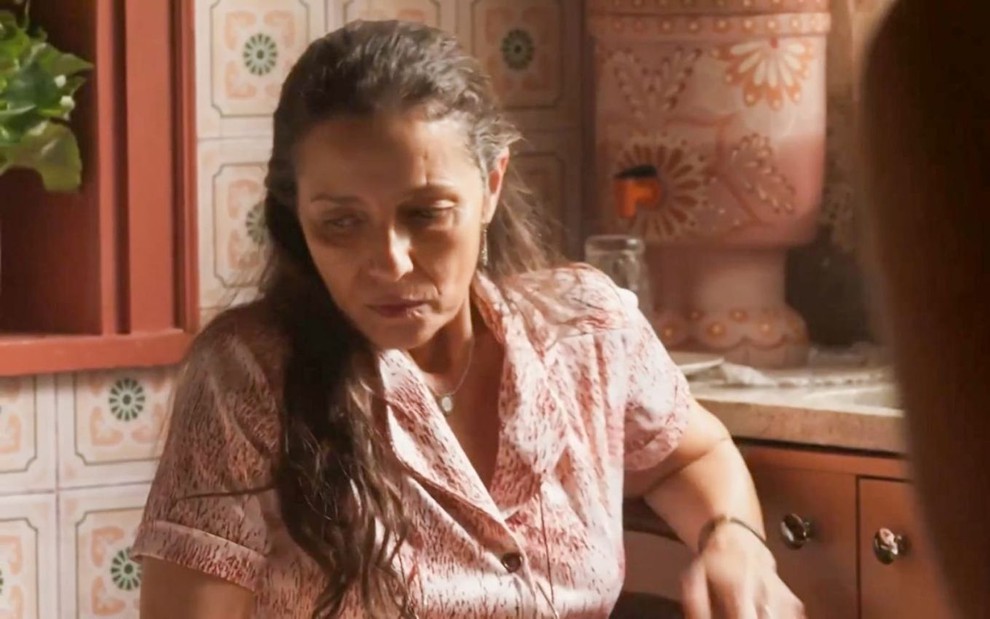A atriz Cyria Coentro como Dodôca em Mar do Sertão; ela está sentada, olhando para baixo com cara de quem está sofrendo