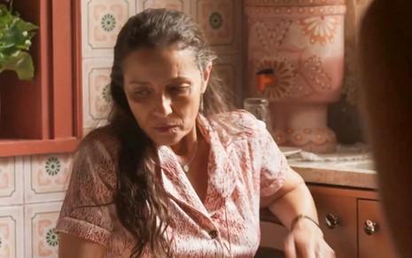 A atriz Cyria Coentro como Dodôca em Mar do Sertão; ela está sentada, olhando para baixo com cara de quem está sofrendo