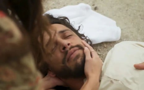 O ator Pedro Lamin como Maruan em Mar do Sertão; ele está caíndo no chão, de olhos fechados, enquanto a atriz Theresa Fonseca (labibe) coloca a mão em seu rosto