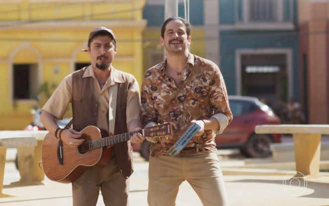 Os repentistas Juzeh e Lukete como Totonho e Palmito em Mar do Sertão; eles estão cantando e dançando, enquanto o primeiro segura e toca uma viola e o segundo toca um pandeiro, sorrindo