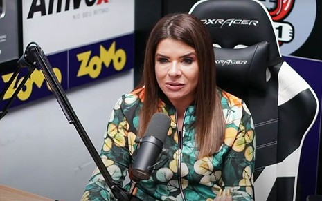 A cantora Mara Maravilha em uma cadeira gamer em frente a um microfone estúdio de gravação