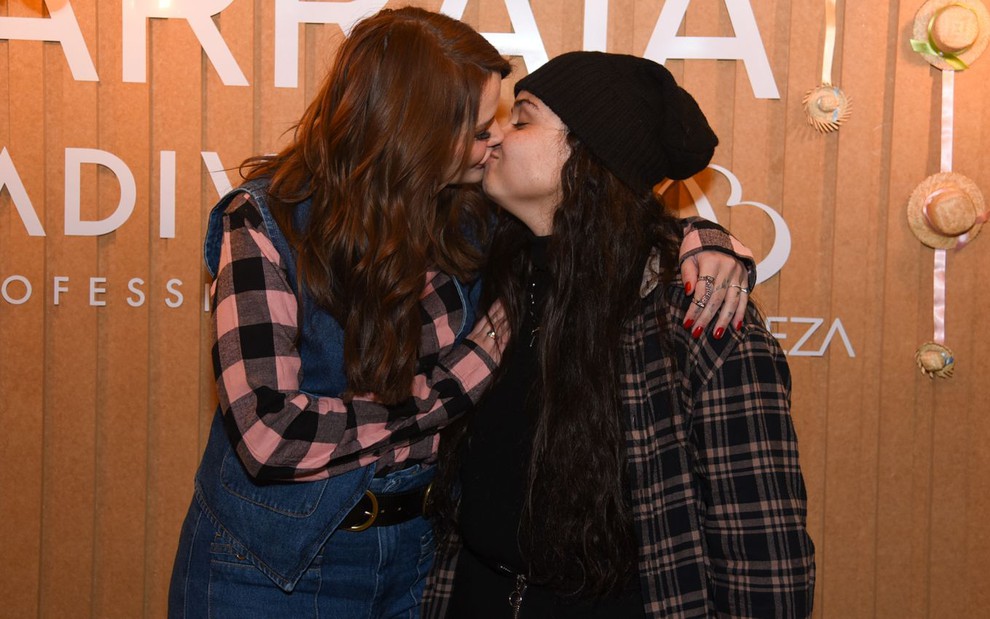 Cantora Luiza e Marcela Mc Gowan, vestidas de quadriculado, trocam beijos em festa junina