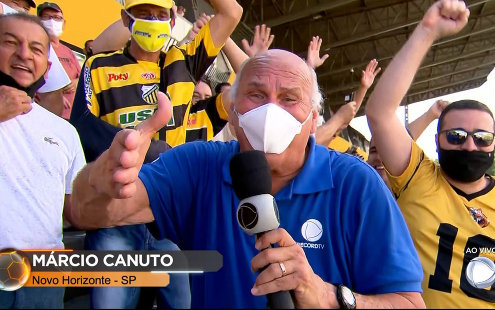 Márcio Canuto no meio da torcida do Novorizontino com uma camisa azul e máscara na transmissão do Campeonato Paulista 2022