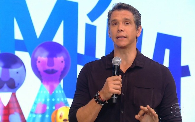 Márcio Garcia está com uma camisa roxa. Ele sorri para a câmera no cenário do Tamanho Família, da Globo.