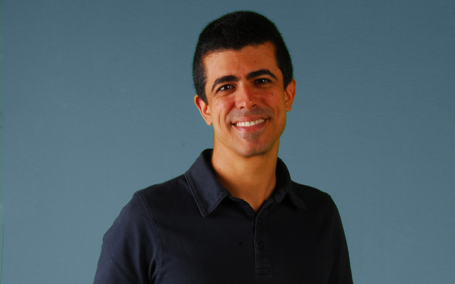 Marcius Melhem usa camisa preta e sorri ao posar para foto