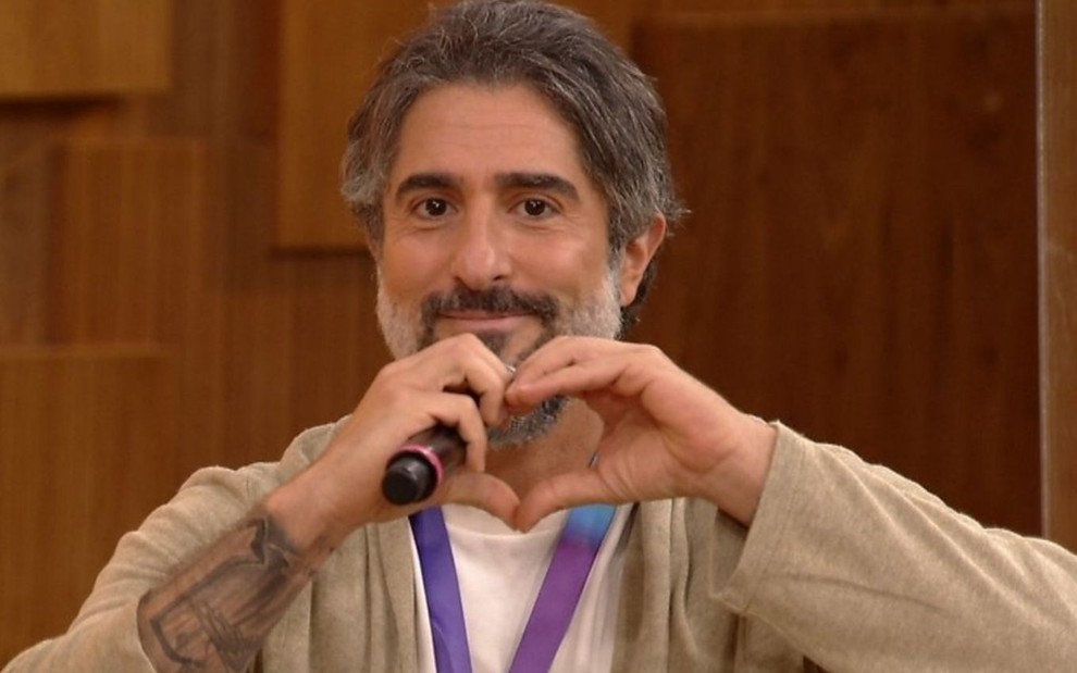 Marcos Mion faz sinal de coração com as mãos durante entrevista no programa Encontro