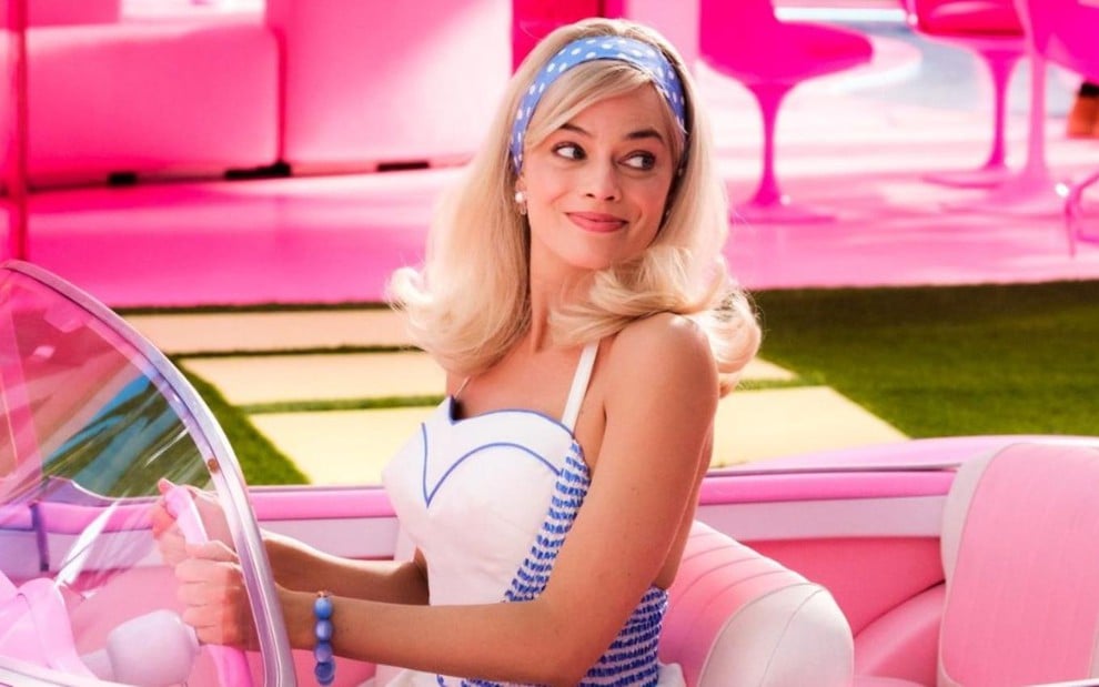 Margot Robbie em cena de Barbie, dentro de um carro rosa, olhando para a direita