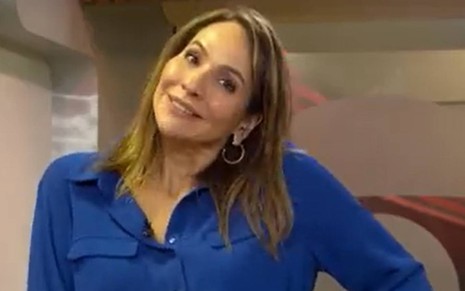 Jornalista Maria Beltrão coloca a cabeça de lado e sorri para a câmera durante telejornal