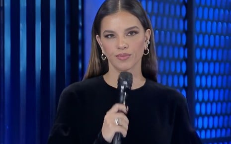 Mariana Rios está séria e com microfone na mão em A Grande Conquista
