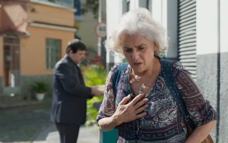 Marieta Severo como Noca em cena de Um Lugar ao Sol: atriz olha para baixo e coloca a mão no peito