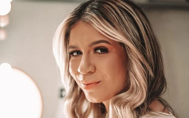 Marília Mendonça está olhando para a câmera, com sorriso discreto