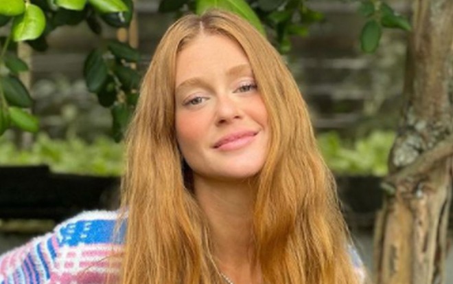 Marina Ruy Barbosa, ruiva, de cabelo comprido solto e blusa azul, rosa, com listras