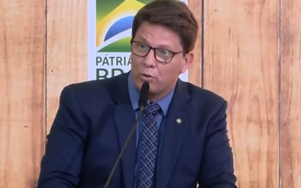 O ator Mario Frias em frente a um púlpito com o logo do governo Bolsonaro ao fundo