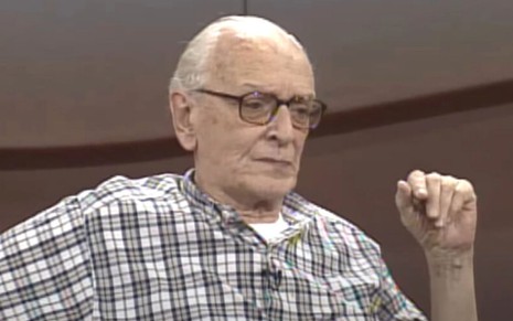 De óculos e camisa xadrez, Mário Lago está sentado em entrevista para o Roda Viva, da Cultura, em 1998
