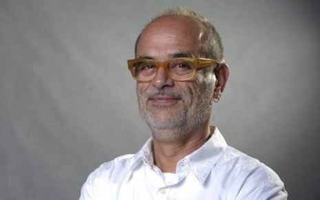 Mário Márcio Bandarra careca, de barba grisalha, camisa branca e óculos de grau com armação amarela