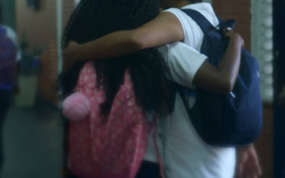 menina abraçando menino de costas em escola