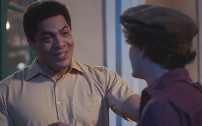 Bento (Matheus Dias) coloca a mão no ombro de Lorenzo (Guilherme Prates), que está de costas em cena da novela Além da Ilusão