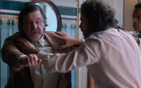 Os atores Antonio Calloni e Eriberto Leão como Matias e Leônidas em Além da Ilusão; o segundo está segurando o primeiro com as mãos durante um surto