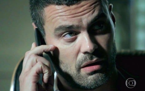 O ator Carmo Dalla Vecchia segura telefone em cena de Império