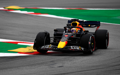 Carro de Fórmula 1 preto e amarelo, da Red Bull, sendo pilotado por Max Verstappen em treino