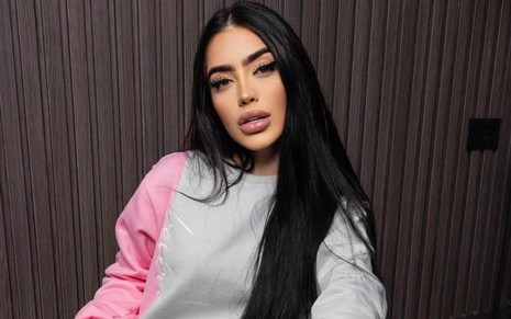A cantora MC Mirella com expressão séria, de moletom cinza e rosa, cabelo liso e solto em foto publicada no Instagram