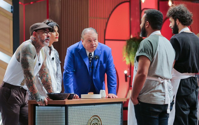 Imagem de Henrique Fogaça, Helena Rizzo e Erick Jacquin, da esquerda para a direita, atrás da bancada avaliando Renato e Rafael no MasterChef 9