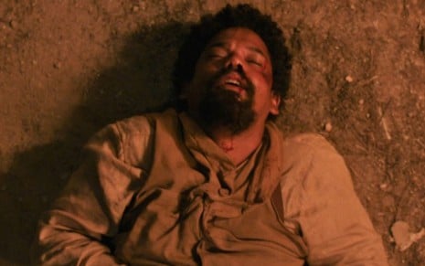 Jorge/Samuel (Michel Gomes) está caído e com ferimentos no rosto em cena de Nos Tempos do Imperador
