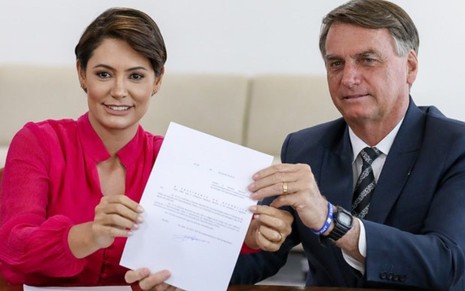 Michelle e Jair Bolsonaro seguram documento com as mãos