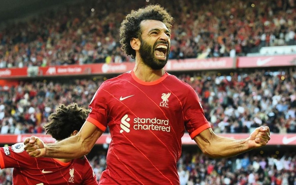 Mo Salah, atacante do Liverpool, comemora gol na Premier League em Anfield, na Inglaterra. Ele usa a camisa vermelha do clube tradicional inglês.