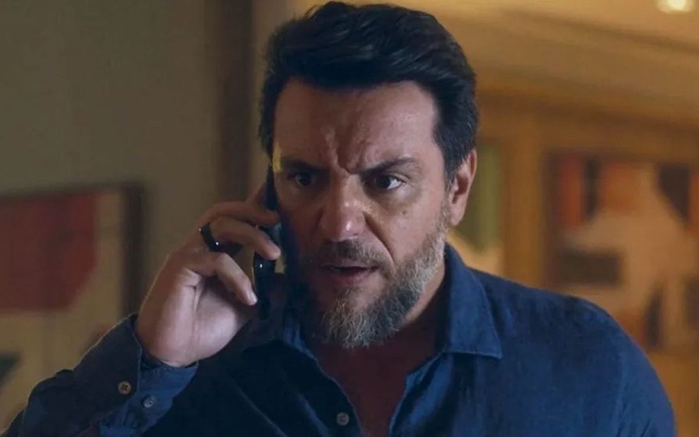 O ator Rodrigo Lombardi com celular no ouvido e expressão de raiva em cena da novela Travessia